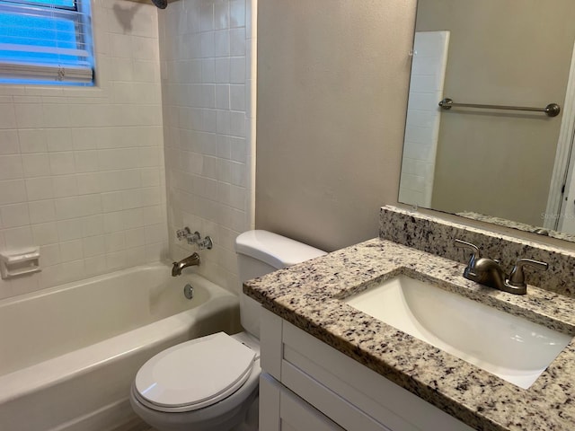 full bathroom featuring tiled shower / bath, vanity, and toilet