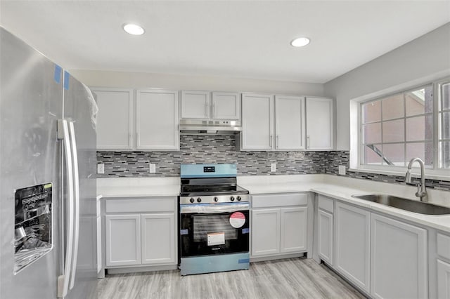 kitchen with sink, white cabinets, backsplash, light hardwood / wood-style floors, and stainless steel appliances