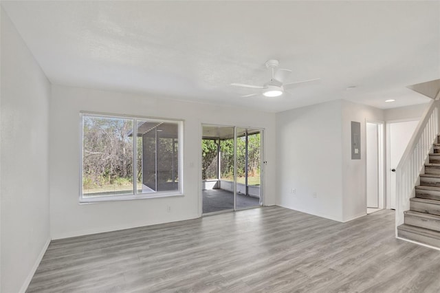 unfurnished room with ceiling fan, electric panel, and light hardwood / wood-style floors