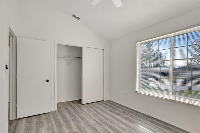 unfurnished bedroom with ceiling fan, vaulted ceiling, a closet, and light wood-type flooring