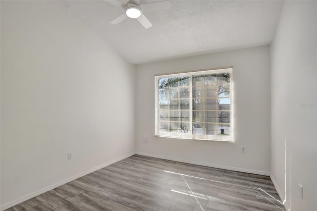 spare room with hardwood / wood-style flooring, vaulted ceiling, and ceiling fan