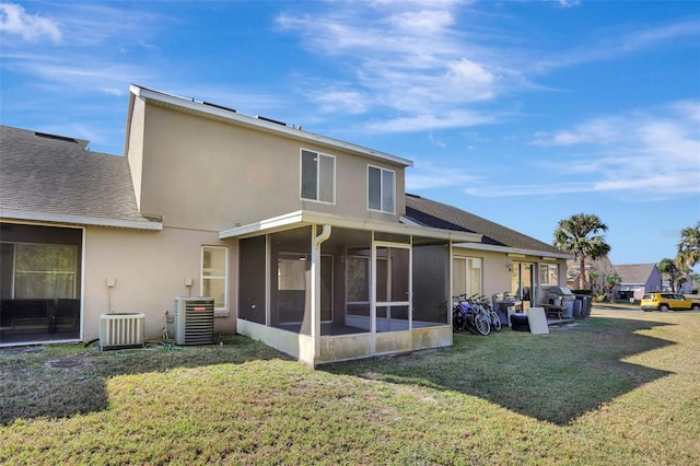 rear view of house featuring a sunroom, cooling unit, and a lawn