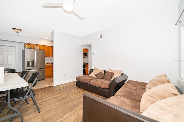 living room featuring ceiling fan and light hardwood / wood-style floors