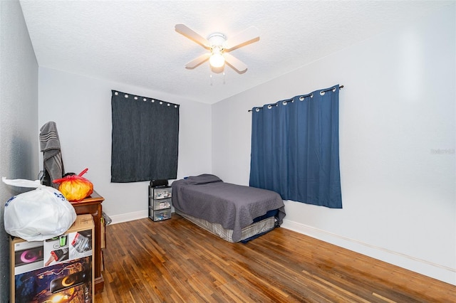 bedroom featuring ceiling fan, dark hardwood / wood-style floors, and a textured ceiling