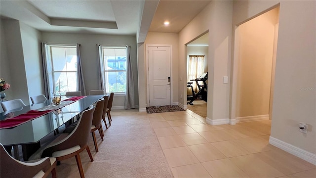 dining space with a tray ceiling and light tile patterned flooring