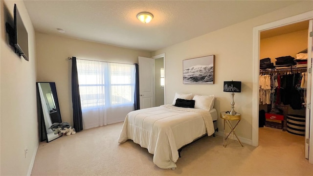 carpeted bedroom featuring a walk in closet, a closet, and a textured ceiling