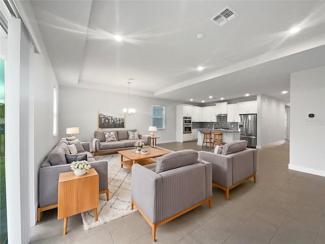 living room with an inviting chandelier and a raised ceiling