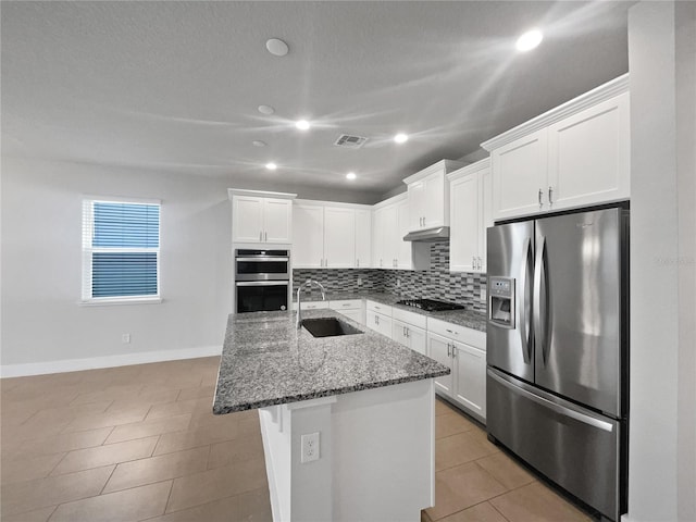 kitchen featuring stainless steel appliances, sink, dark stone countertops, and white cabinets