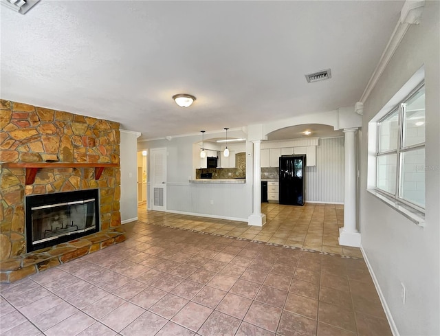 unfurnished living room with crown molding, tile patterned floors, a stone fireplace, and decorative columns