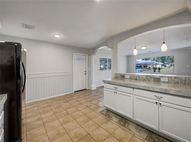 kitchen with black fridge, pendant lighting, white cabinets, and light tile patterned floors