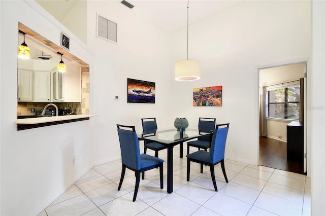 dining space featuring light tile patterned flooring, sink, and a high ceiling