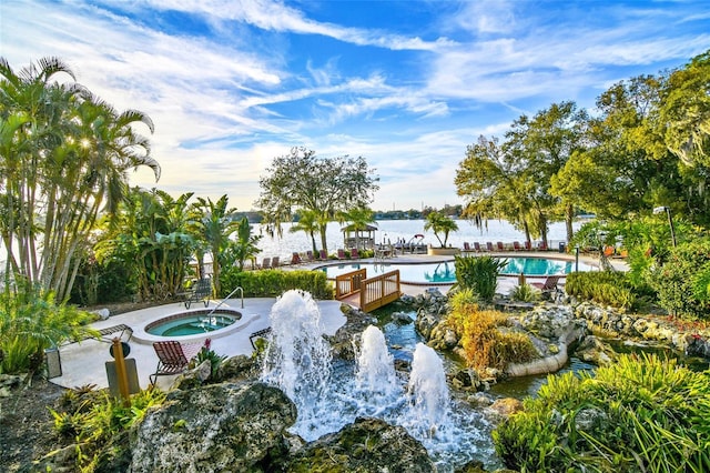 view of community featuring a water view and a pool with hot tub