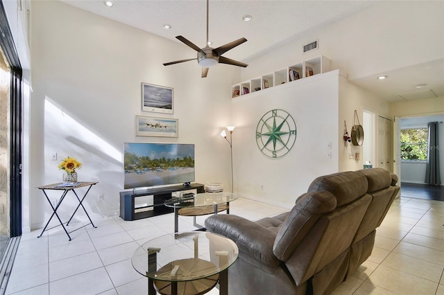 tiled living room featuring ceiling fan and a high ceiling