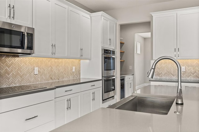 kitchen with sink, decorative backsplash, stainless steel appliances, and white cabinets