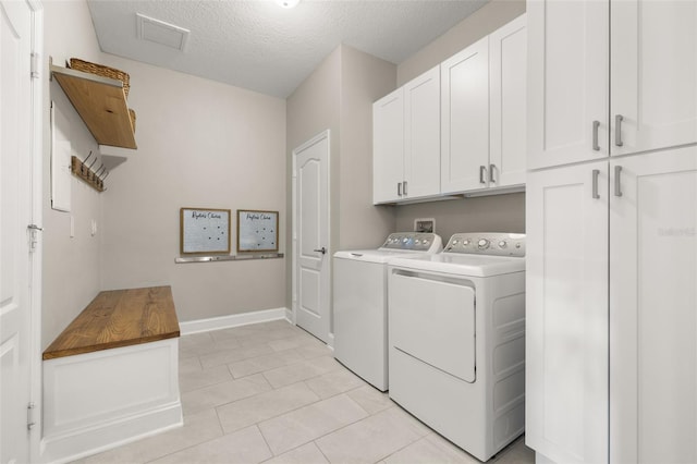 laundry room featuring cabinets, washer and dryer, light tile patterned floors, and a textured ceiling