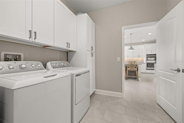 washroom with washer and clothes dryer, cabinets, and light tile patterned flooring