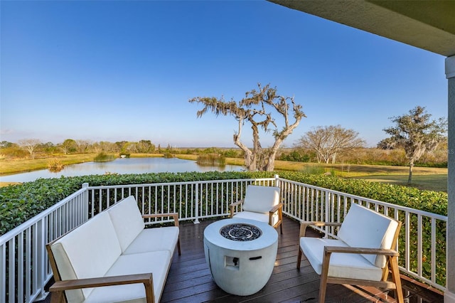 wooden deck with an outdoor living space with a fire pit and a water view