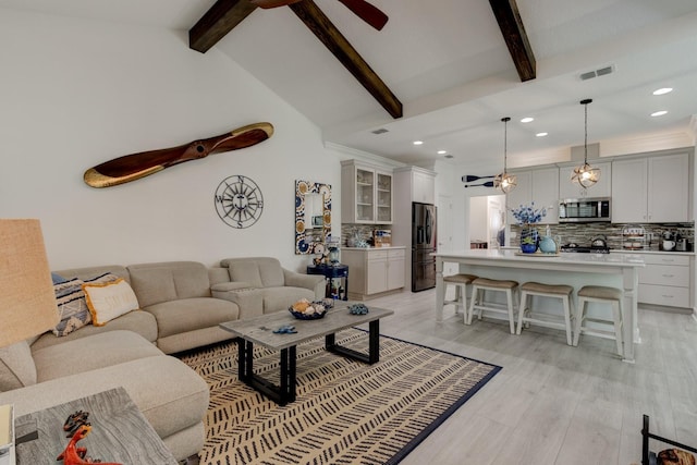 living room featuring ceiling fan, vaulted ceiling with beams, and light hardwood / wood-style floors