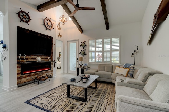 living room with lofted ceiling with beams, a stone fireplace, an inviting chandelier, and light hardwood / wood-style flooring