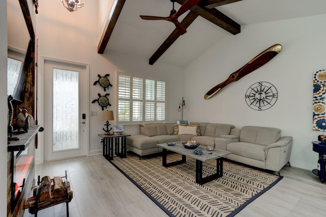 living room featuring ceiling fan, plenty of natural light, beamed ceiling, and light wood-type flooring