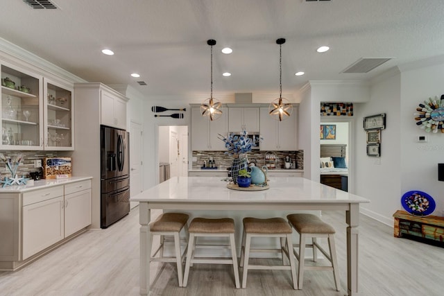 kitchen featuring a kitchen island, crown molding, black fridge, and decorative light fixtures