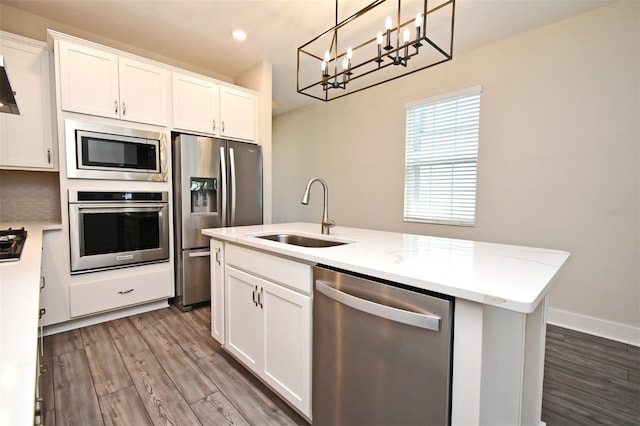 kitchen featuring a kitchen island with sink, decorative light fixtures, stainless steel appliances, and white cabinets