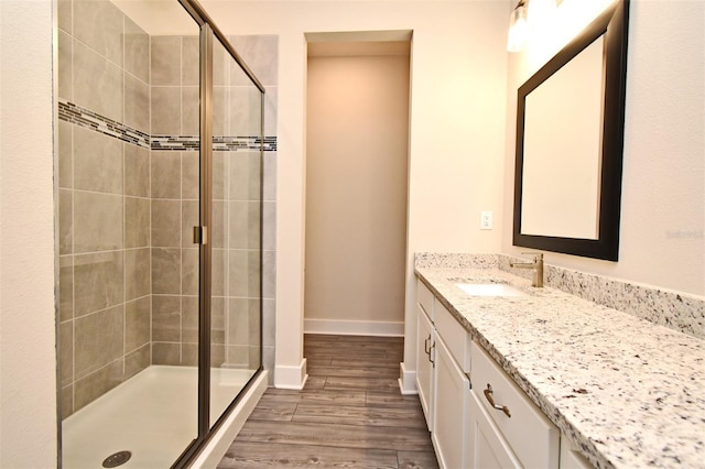 bathroom featuring wood-type flooring, a shower with shower door, and vanity