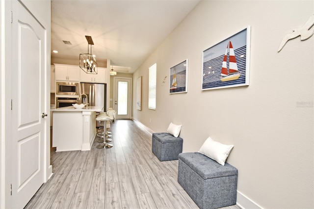 interior space featuring baseboards, a notable chandelier, visible vents, and light wood-style flooring
