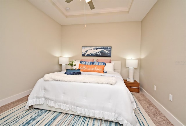 carpeted bedroom with baseboards, a tray ceiling, and ceiling fan