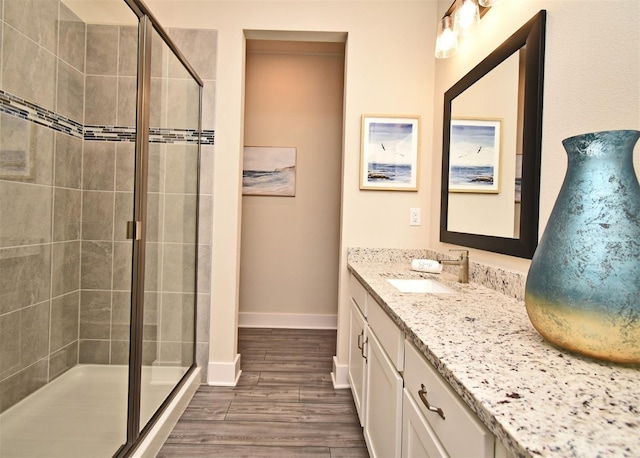 full bath featuring a stall shower, baseboards, wood finished floors, and vanity