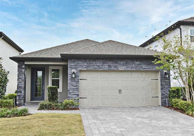view of front of property featuring stone siding, a garage, roof with shingles, and decorative driveway