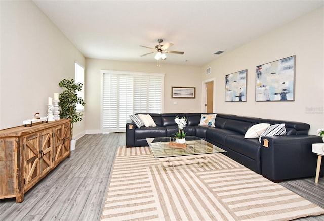 living area featuring baseboards, visible vents, wood finished floors, and a ceiling fan