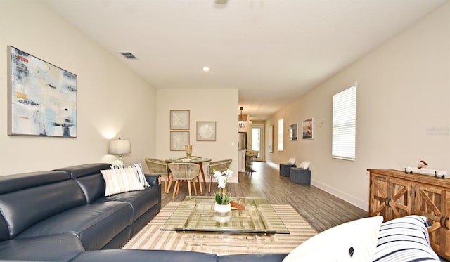 living area with baseboards, visible vents, and wood finished floors