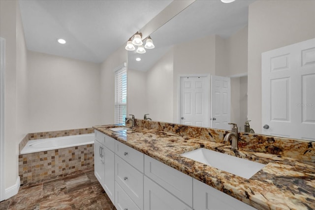 bathroom with vanity and tiled tub