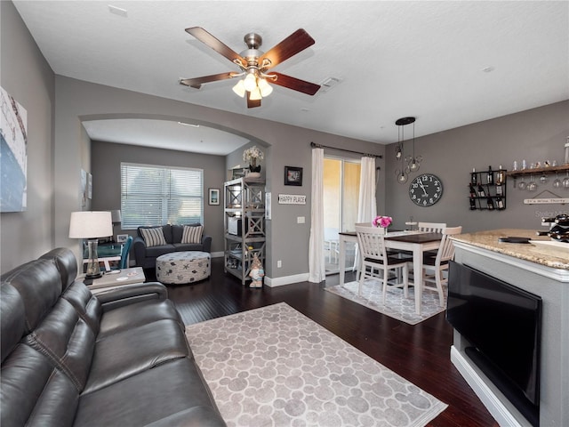 living room featuring dark wood-type flooring and ceiling fan