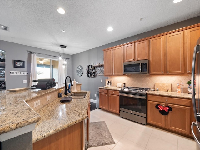 kitchen with appliances with stainless steel finishes, pendant lighting, sink, backsplash, and light stone countertops