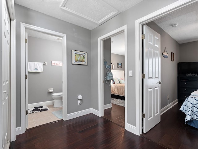 bedroom featuring ensuite bathroom, dark hardwood / wood-style floors, and a textured ceiling