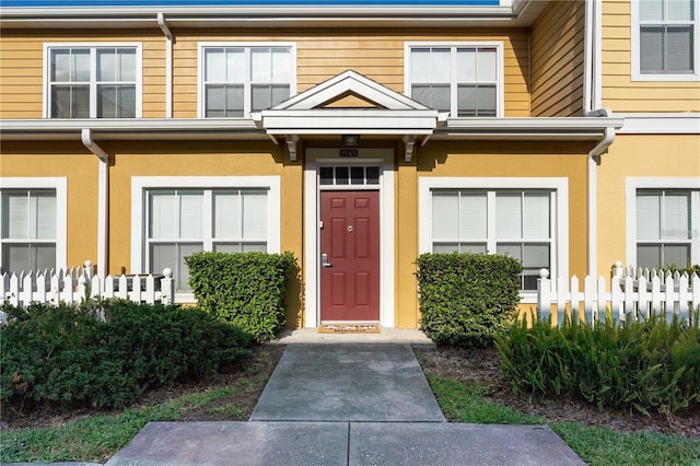 view of exterior entry featuring fence and stucco siding