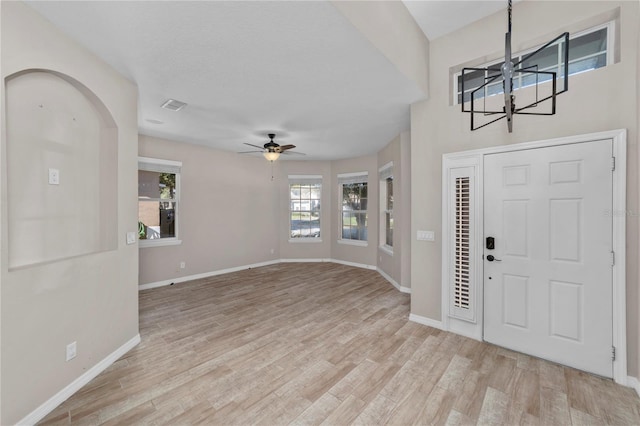 foyer with ceiling fan with notable chandelier and light wood-type flooring