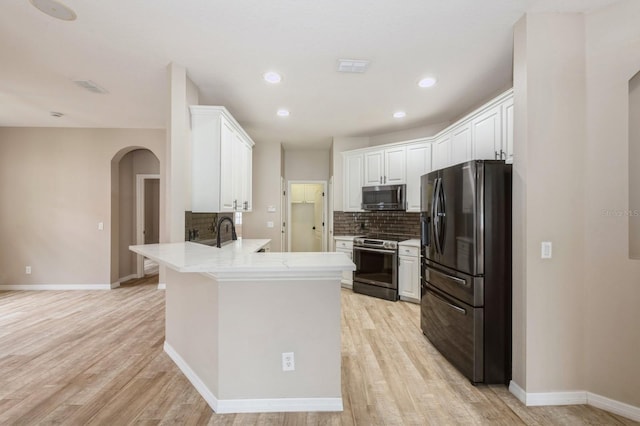 kitchen featuring white cabinetry, stainless steel appliances, tasteful backsplash, light hardwood / wood-style floors, and kitchen peninsula