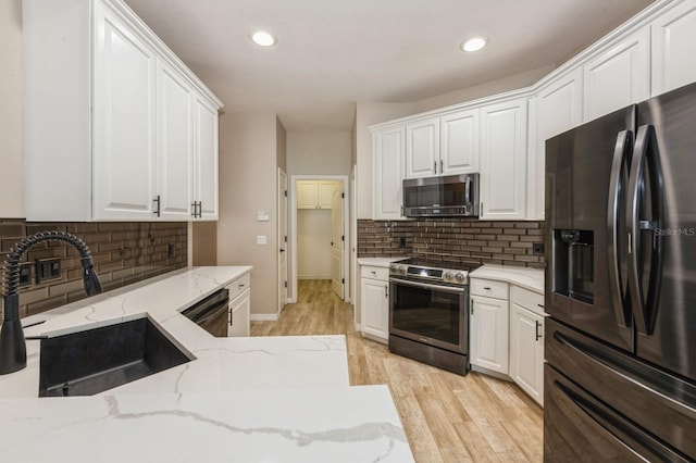 kitchen featuring stainless steel appliances, white cabinetry, and sink