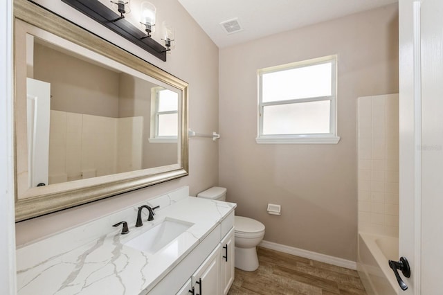 full bathroom with washtub / shower combination, vanity, toilet, and hardwood / wood-style floors