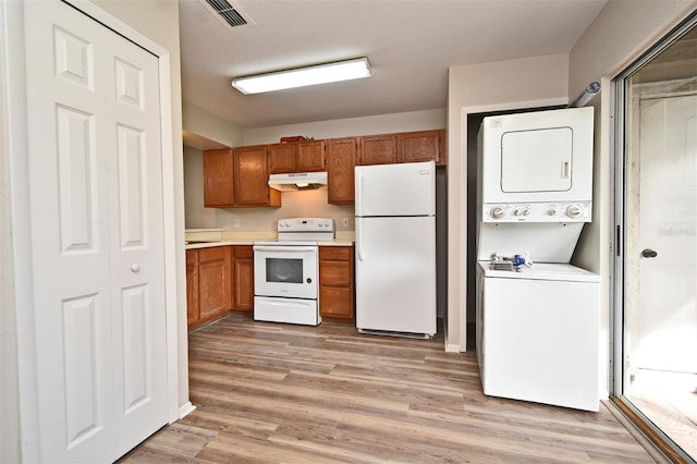 kitchen featuring stacked washer and clothes dryer, light wood-type flooring, and white appliances