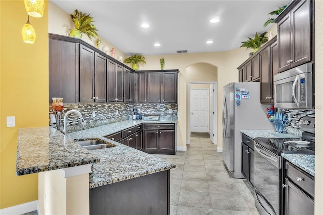 kitchen with appliances with stainless steel finishes, sink, pendant lighting, and light stone counters