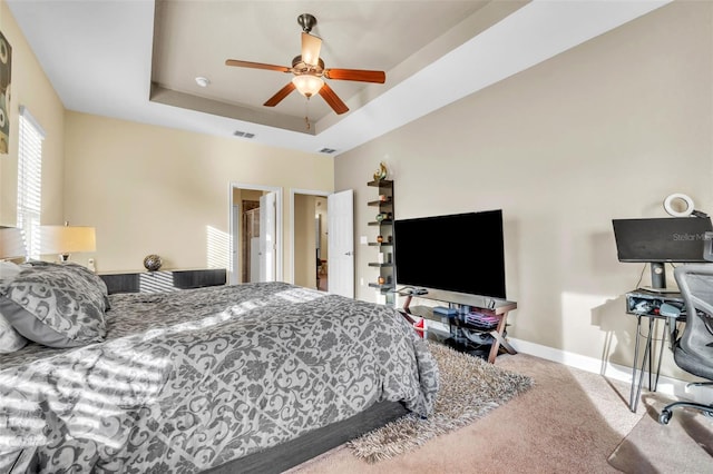 bedroom with carpet floors, a raised ceiling, and ceiling fan