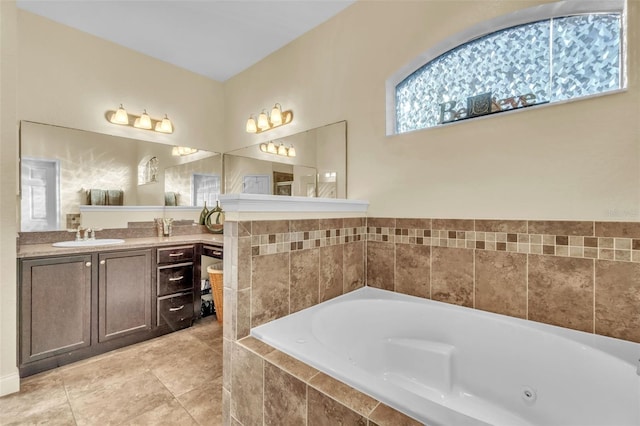 bathroom with tiled tub, vanity, and tile patterned flooring