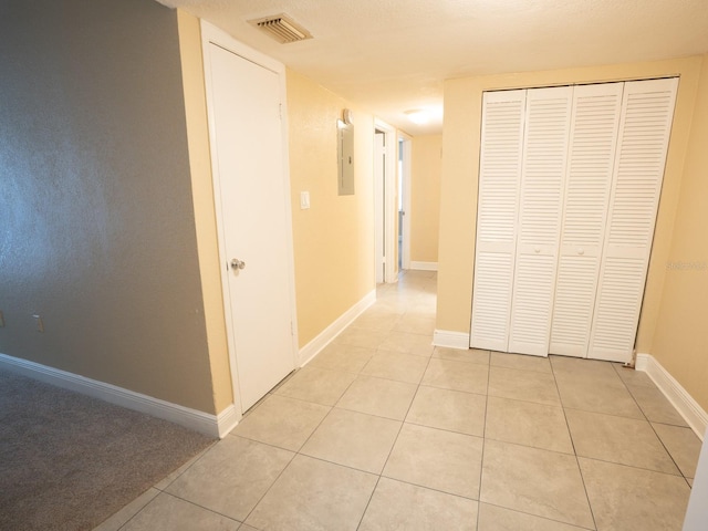 hall with light tile patterned floors and electric panel