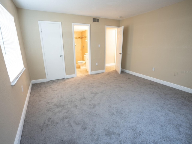 unfurnished bedroom with connected bathroom and light carpet