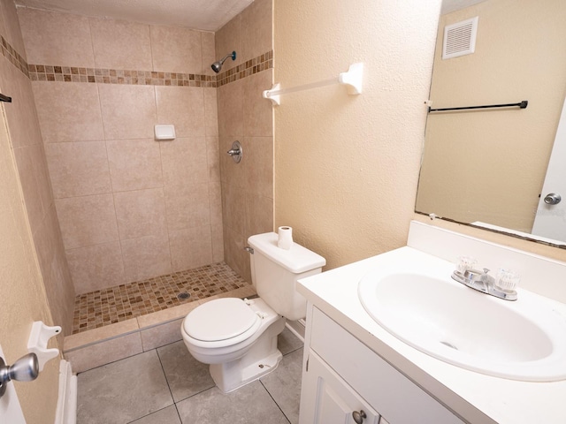 bathroom with tiled shower, vanity, toilet, and tile patterned flooring