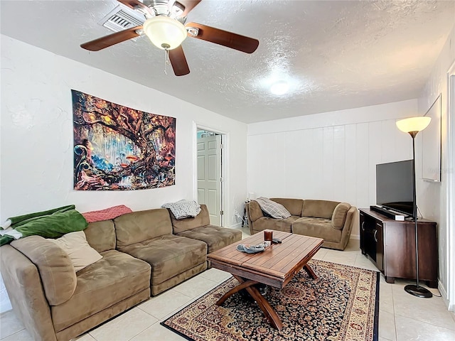 living area featuring a ceiling fan, a textured ceiling, and light tile patterned flooring